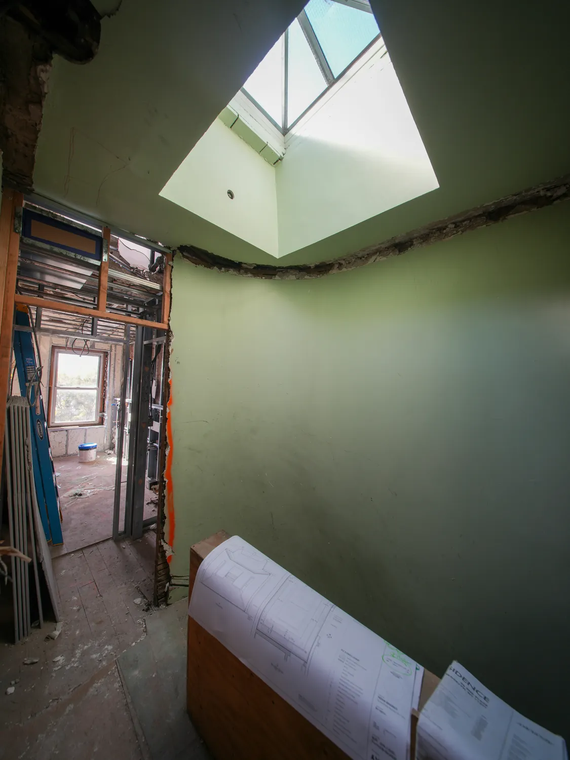 Interior construction space beneath a skylight with plans in the foreground